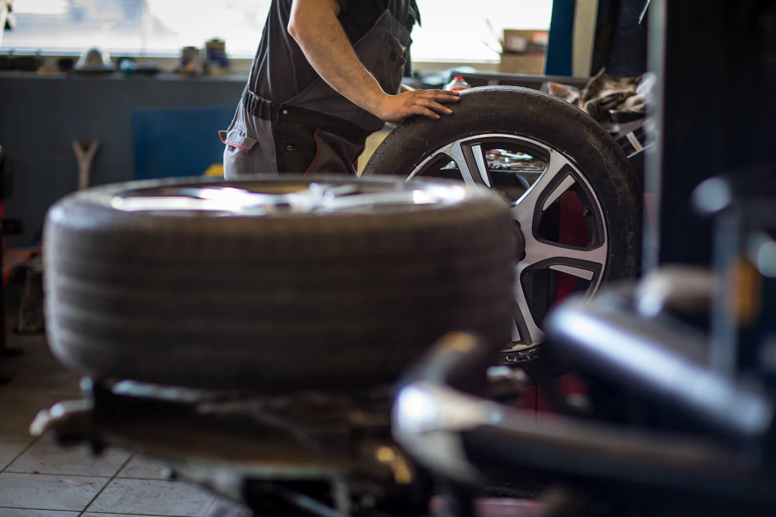 Employee rolling tire in mechanic shop in Texas