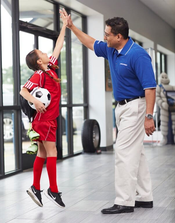 Young soccer player high-fiving tire salesman