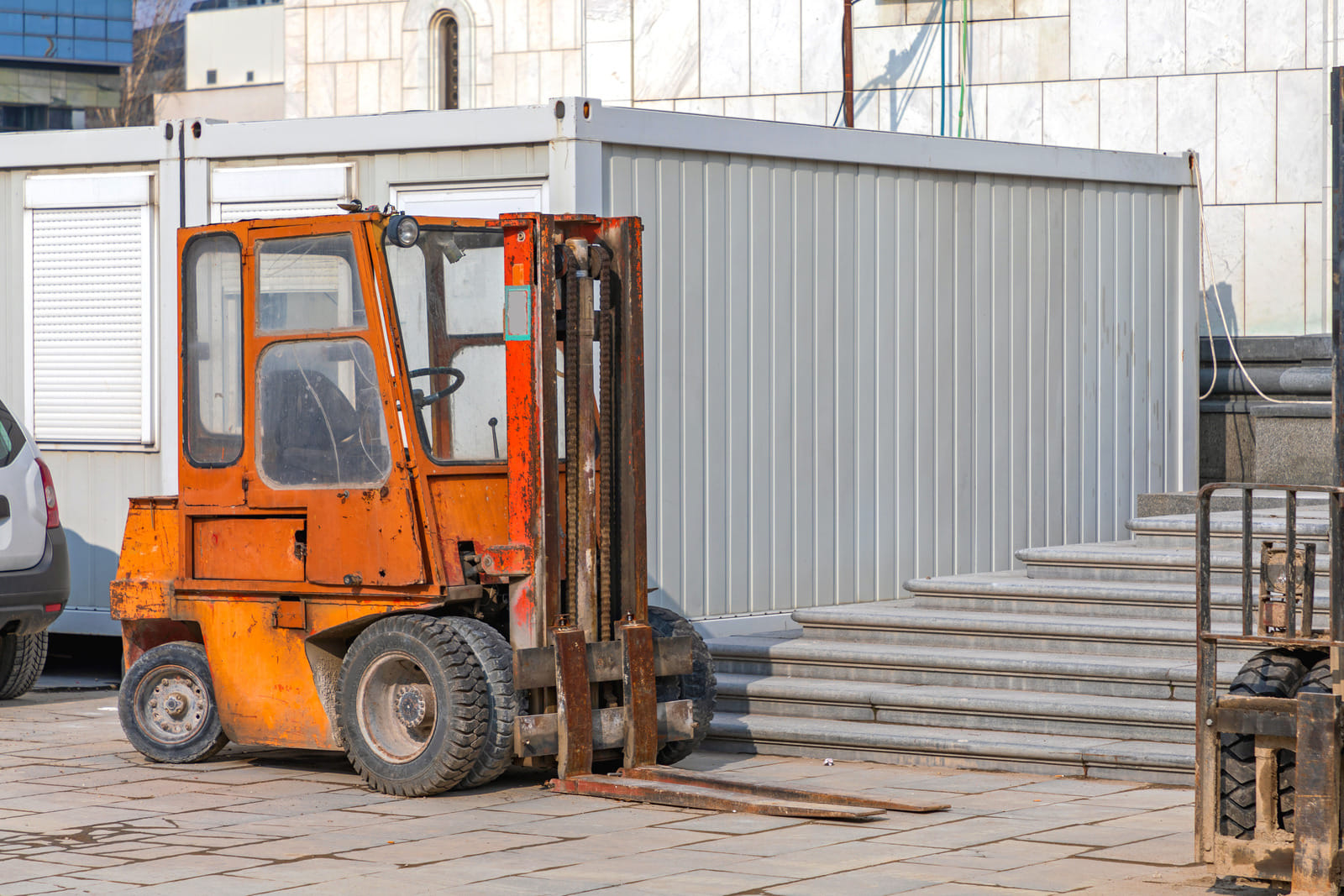 orange forklift sitting outside construction site