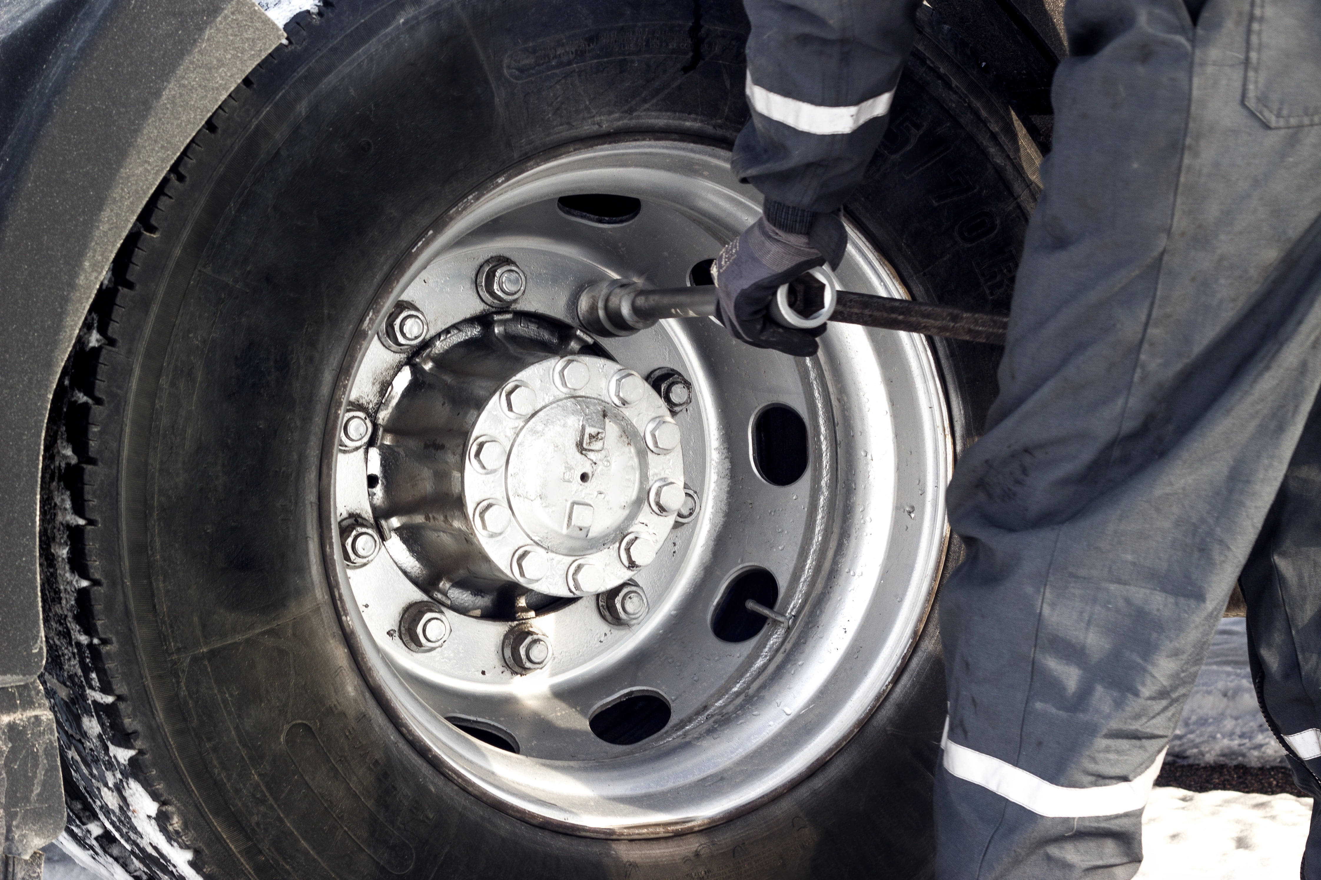 Expert mechanic is unscrewing the tire of a commercial vehicle