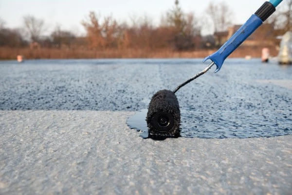 Roller applying waterproof coating on flat roof