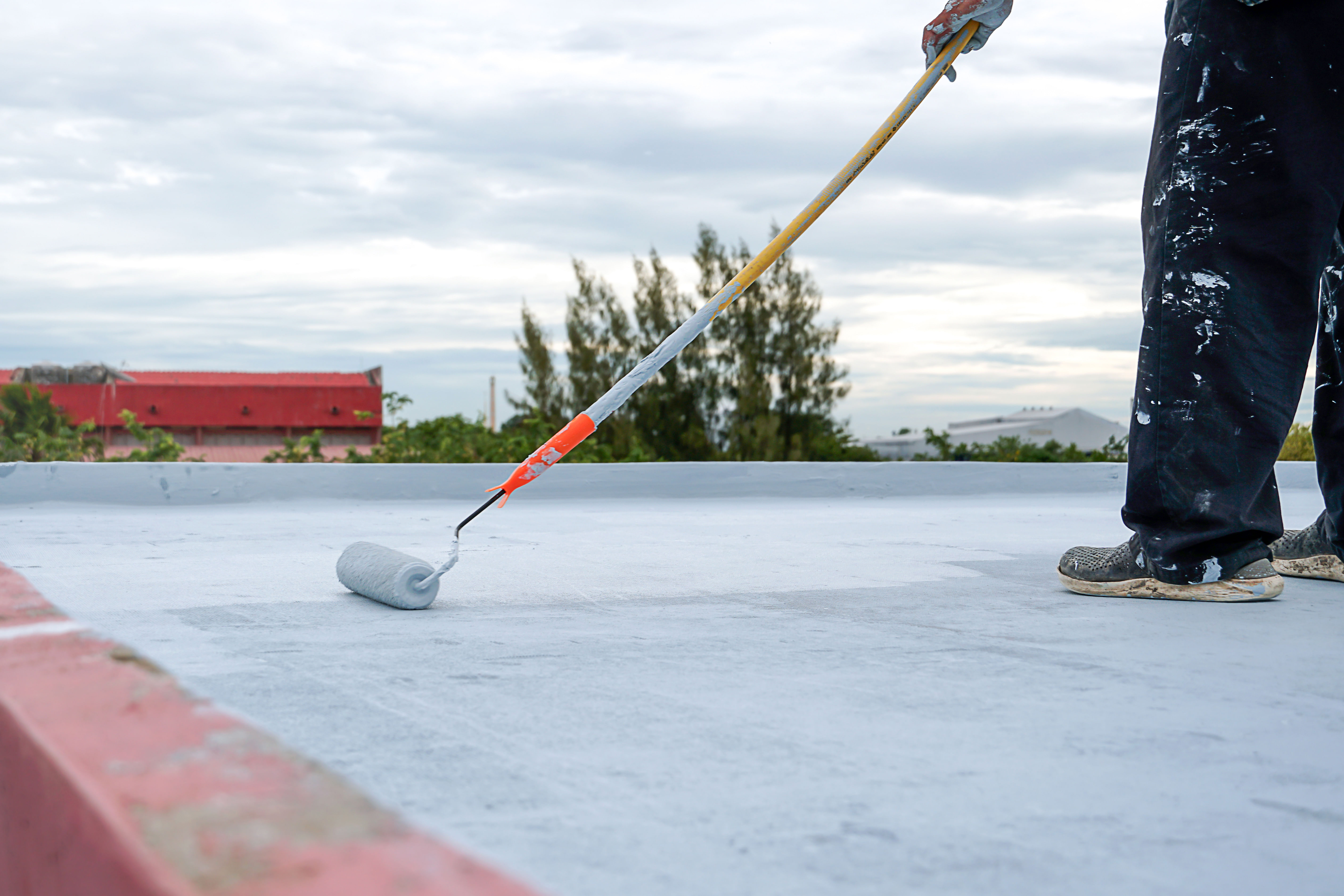 worker spreading coating on roof