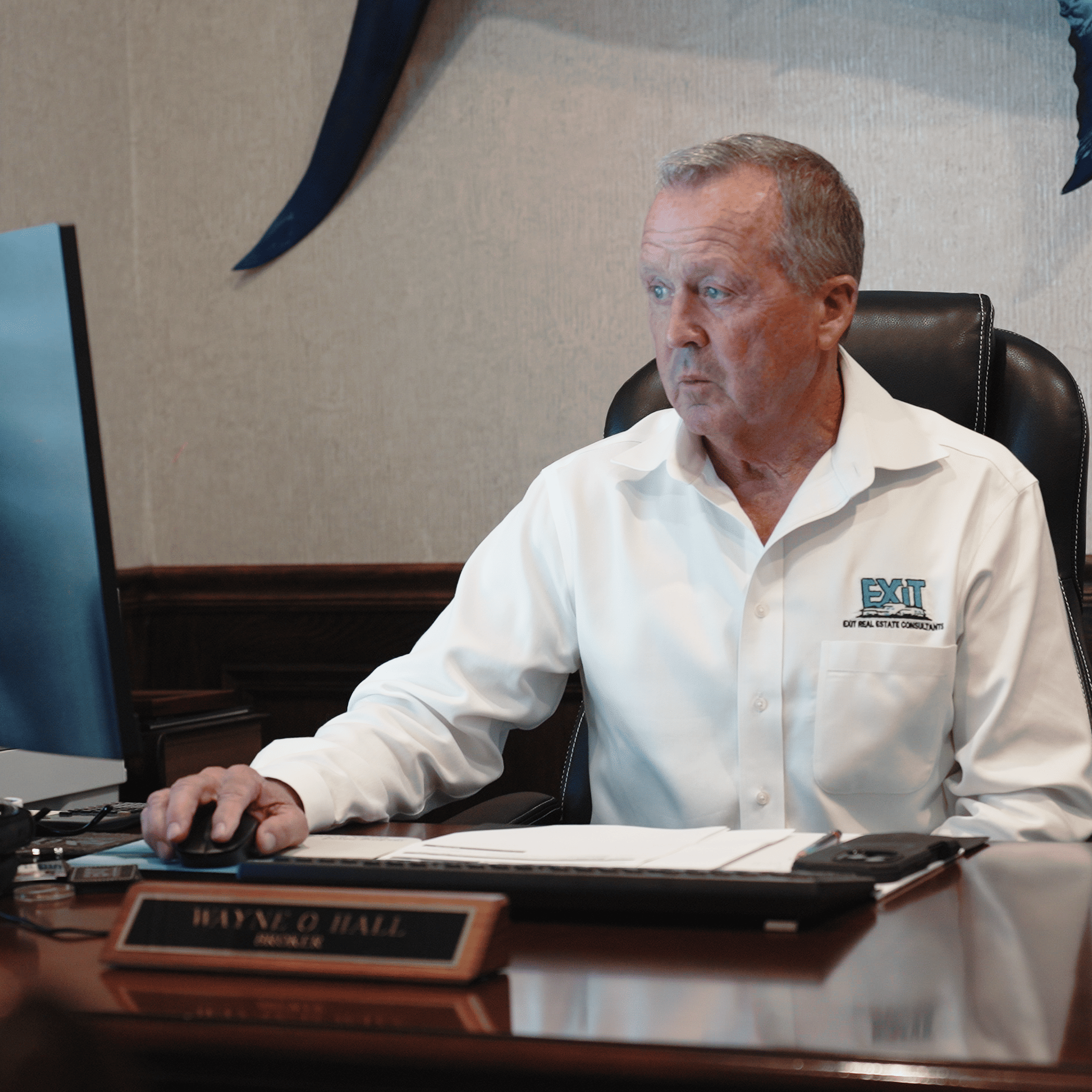 Broker Working at an Executive Desk Real estate broker working at a computer inside an executive office while reviewing documents and managing daily business operations