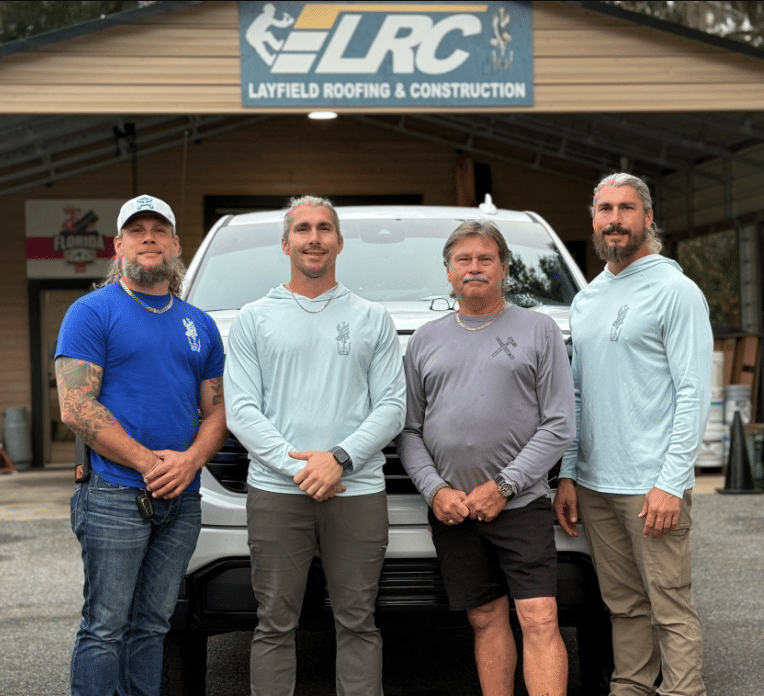 Layfield Roofing and Construction team standing in front of company truck and shop