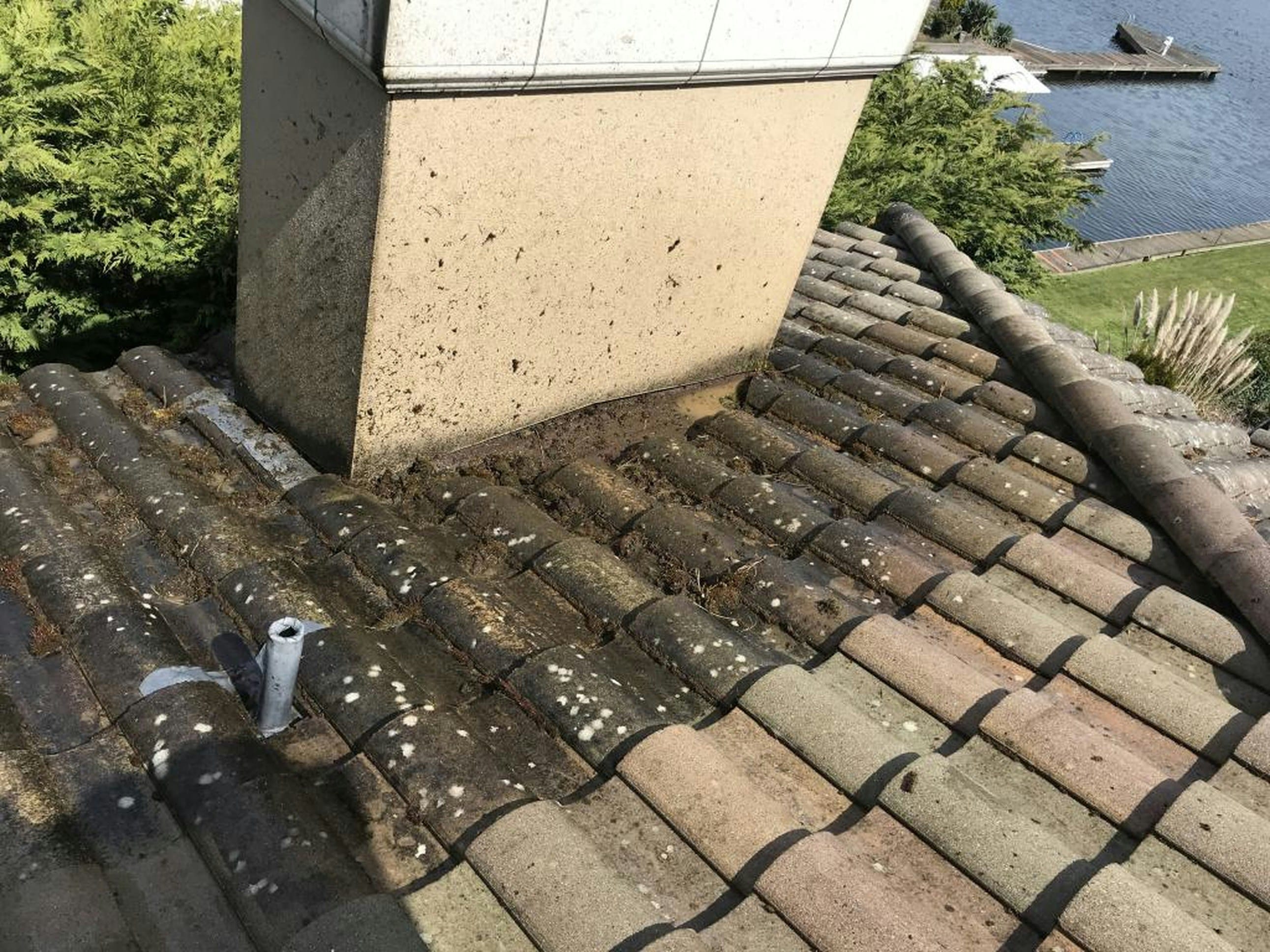 Roof damage and debris buildup around chimney showing need for roof repair Roof damage and debris buildup around chimney showing need for roof repair