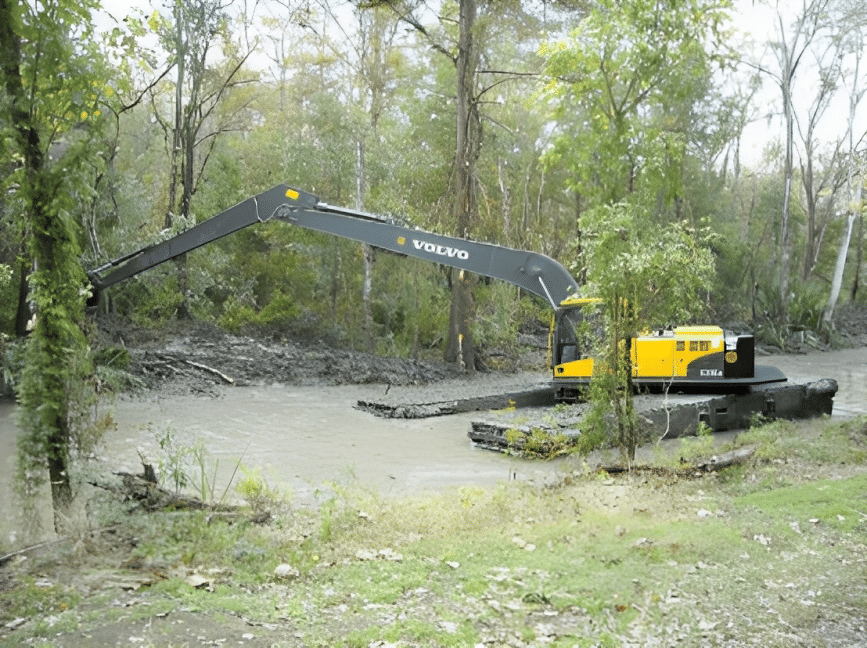 Excavator dredging in the water in swampy, forest area