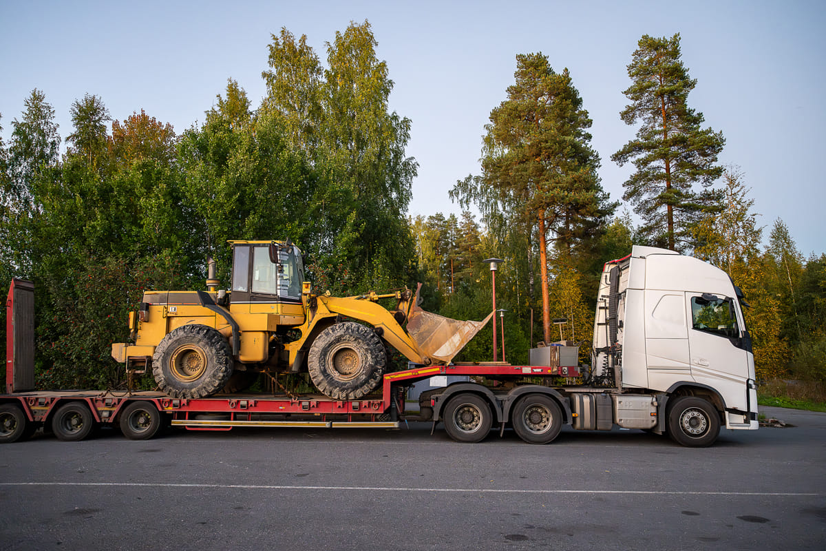commercial truck moving amphibious excavator on trailer