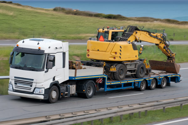 commercial truck hauling excavator on trailer