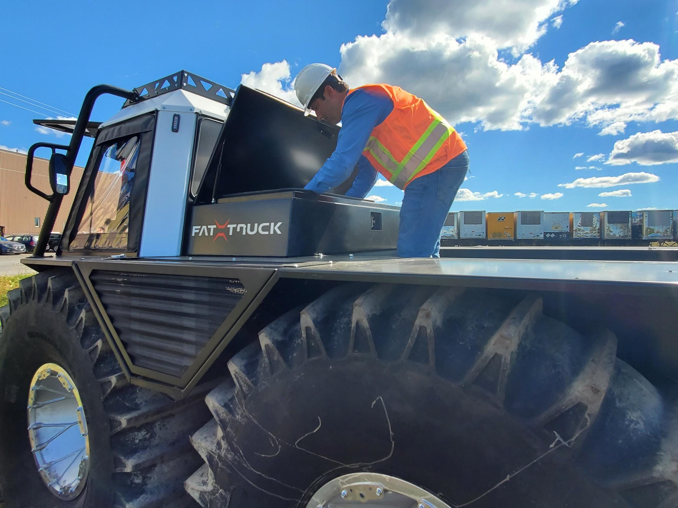 Fat Truck driver in orange vest looking into storage of Fat Truck
