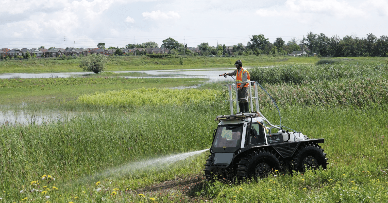 Fat Truck driver is standing on the truck as he sprays field