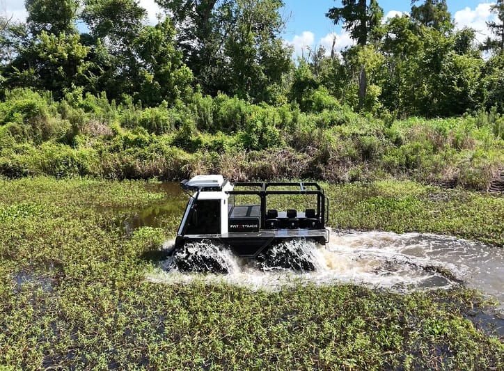 white fat truck driving through marsh