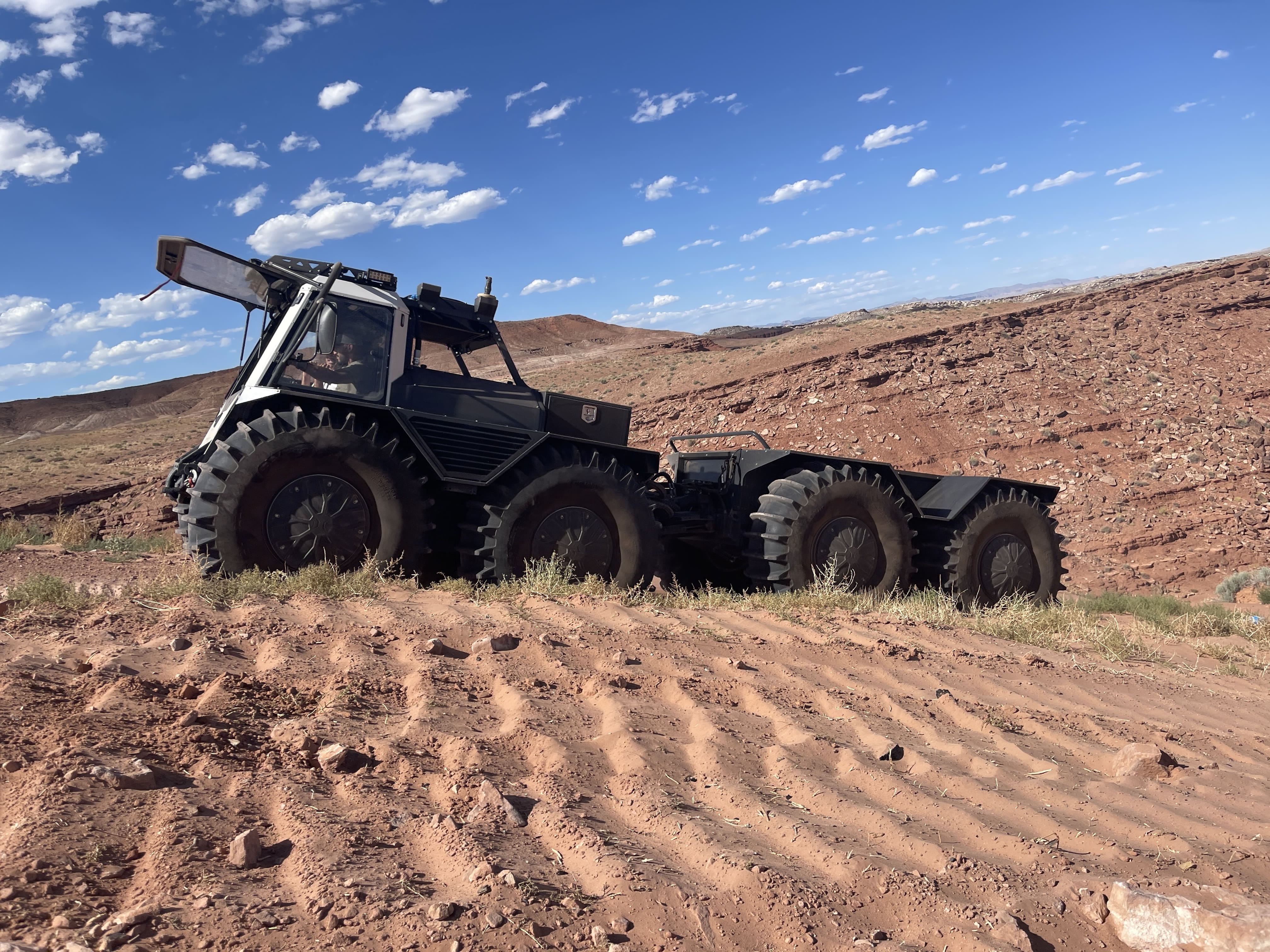 Fat Truck driving on dirt terrain during a job on a partly cloudy day.