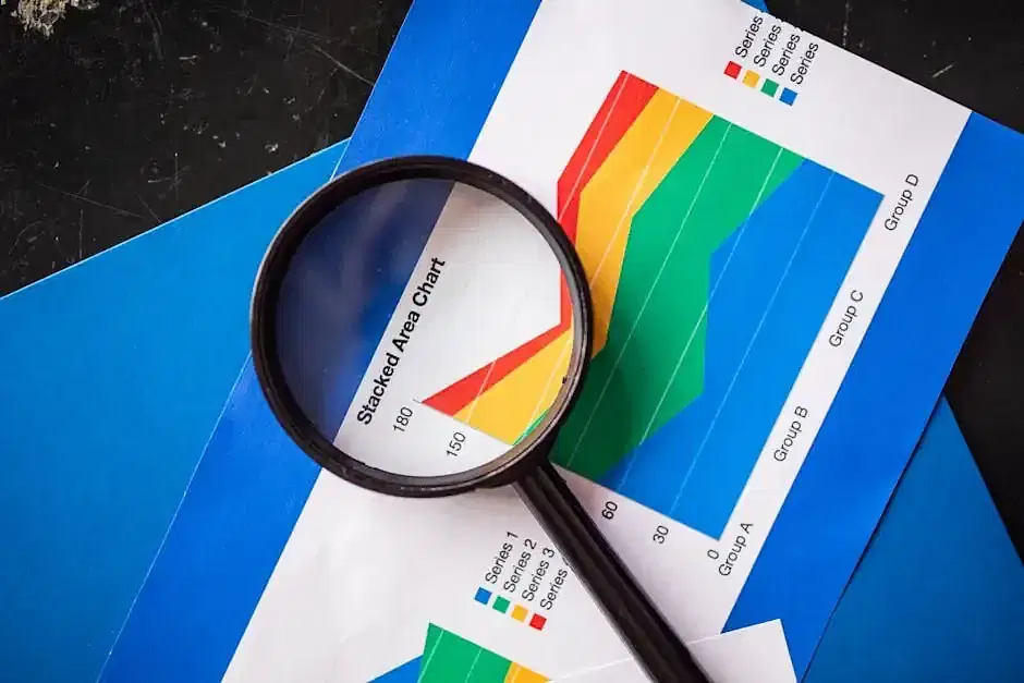 Close-up of a colorful stacked area chart with a magnifying glass highlighting franchise profit and loss analysis data amid blue folders