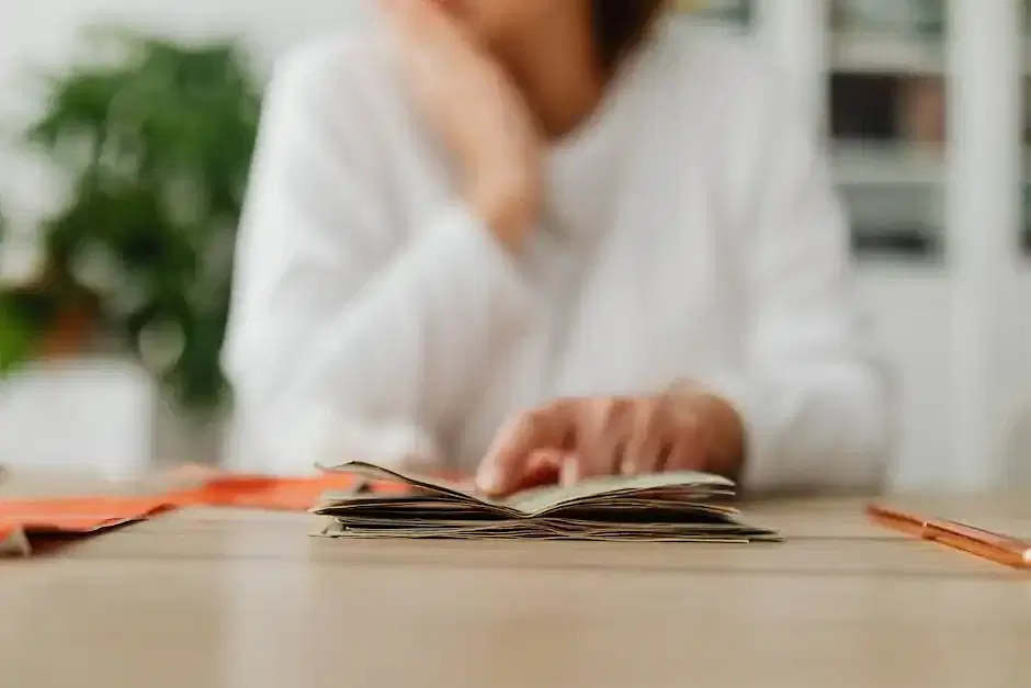 Woman Sitting Behind the Desk and Looking at Money and Receipts 