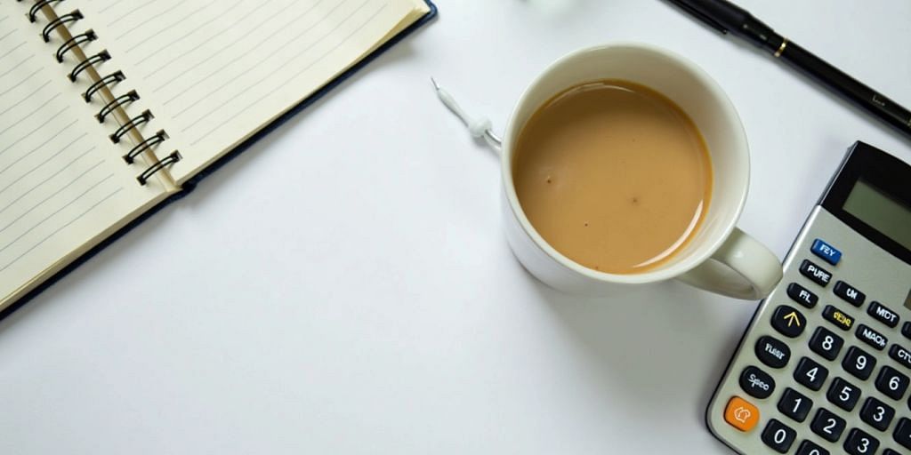 Minimalist desk with coffee, calculator, and open book.
