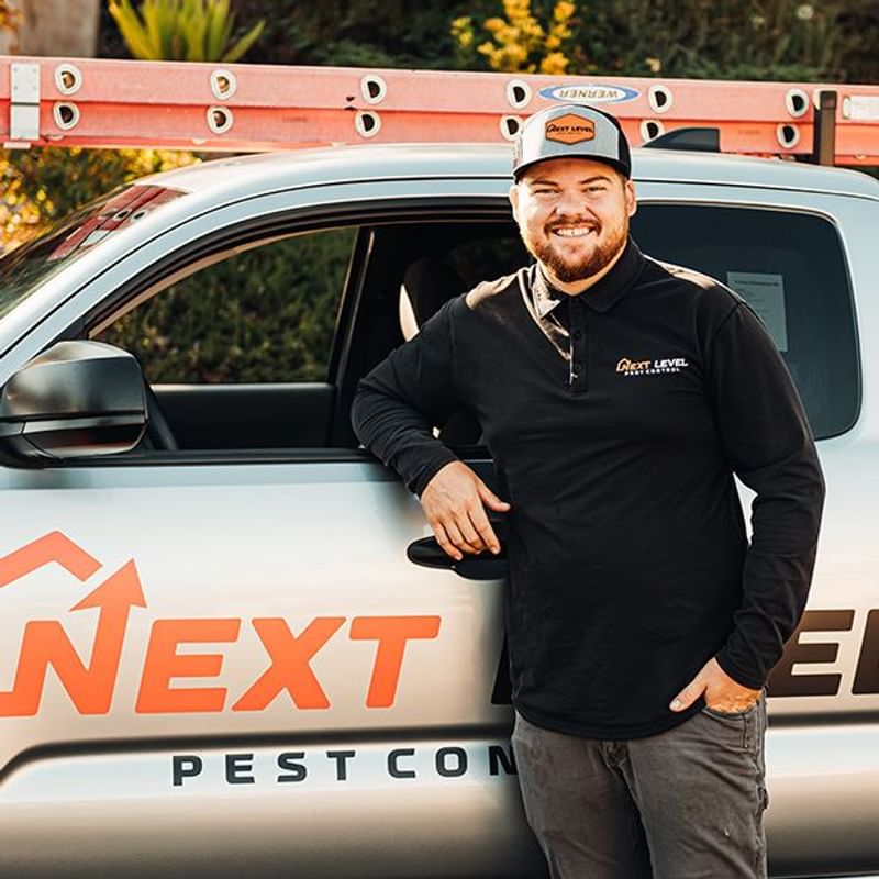 Technician standing by branded Next Level Pest Control truck Technician standing by branded Next Level Pest Control truck