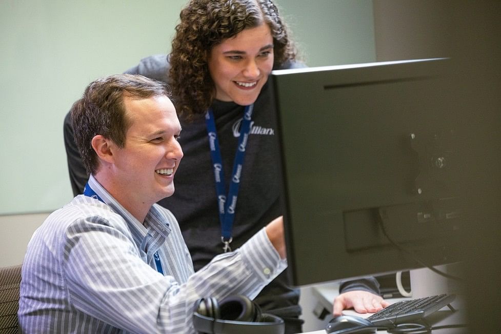 Two IT professionals collaborating at a computer workstation in a modern office, reviewing systems and IT solutions.