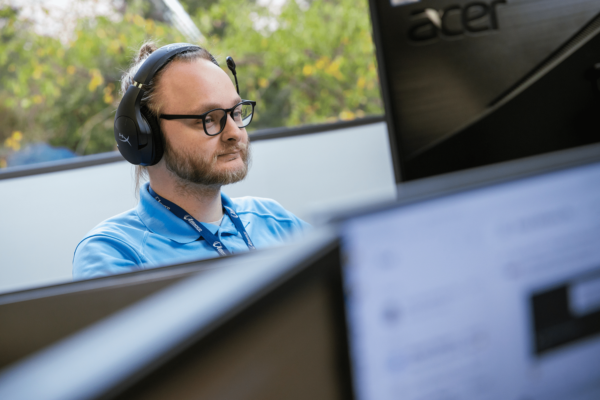 IT professional wearing a headset working at a desktop station in a modern office environment, focused on delivering technical support.