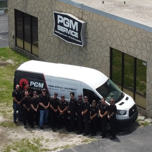PGM Service team standing outside company facility with service vehicle