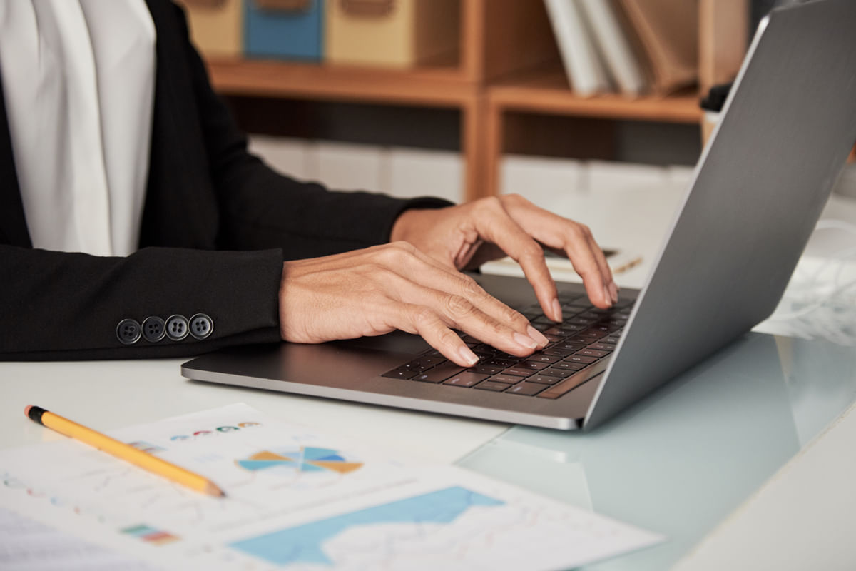 Hands typing on a laptop while preparing tax documents for filing