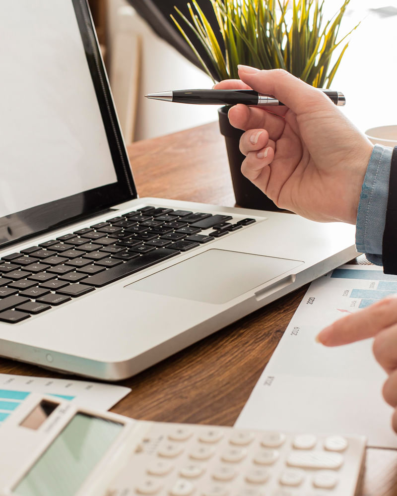 Person pointing at laptop screen with a pen in modern office