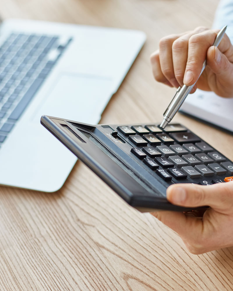 Hands using a calculator with financial notes and a keyboard nearby