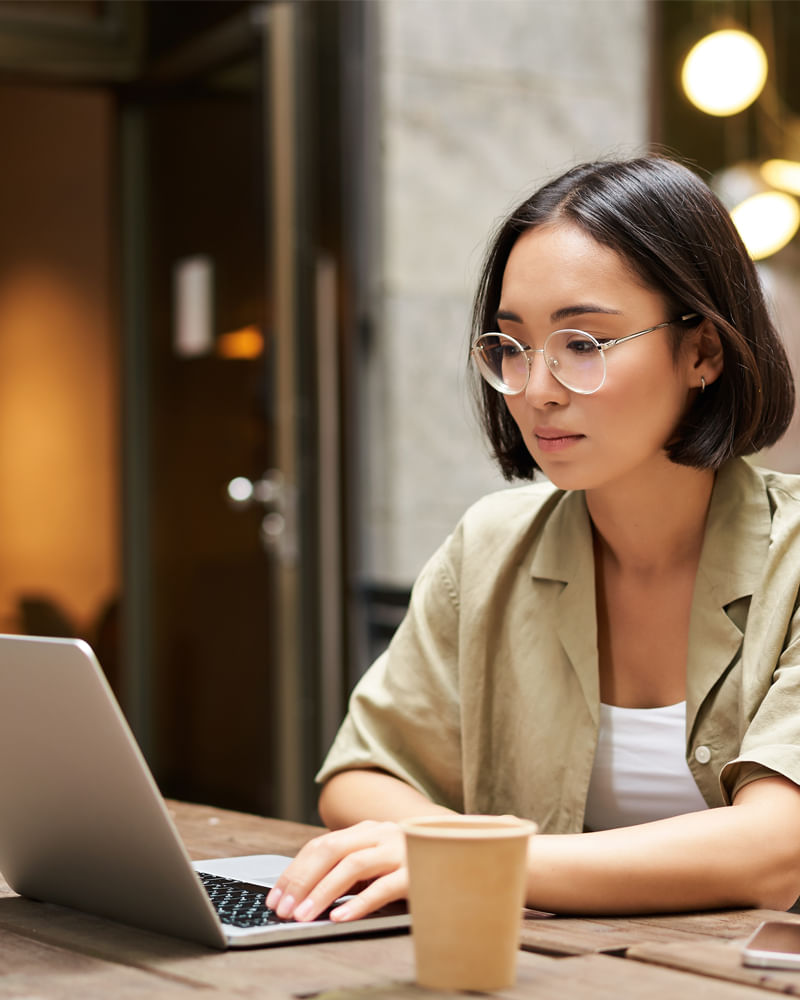 Focused woman working on her taxes online with a laptop and coffee cup