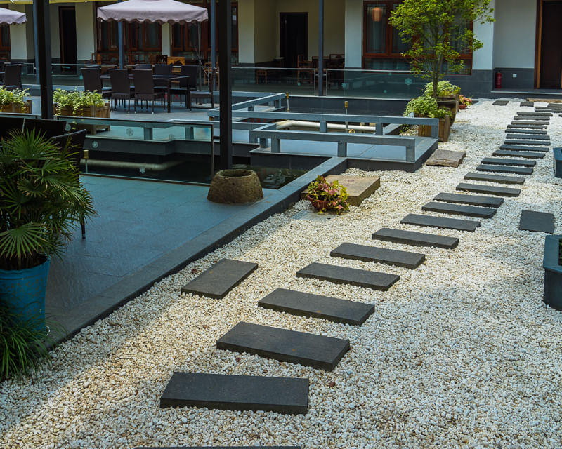 Modern courtyard with stepping stone pathway and planted areas, representing hardscape installation and site design for developments.