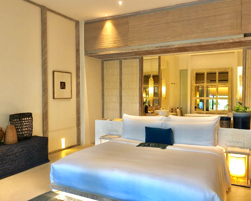 Neatly arranged hotel guest room with king-size bed and warm lighting Neatly arranged hotel guest room with king-size bed and warm lighting