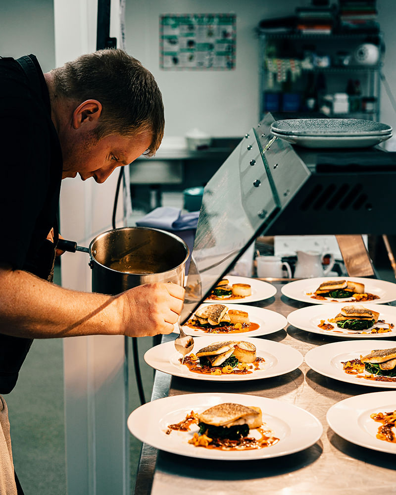 Chef preparing plated dishes in a clean commercial kitchen maintained by restaurant pest control services Chef preparing plated dishes in a clean commercial kitchen maintained by restaurant pest control services