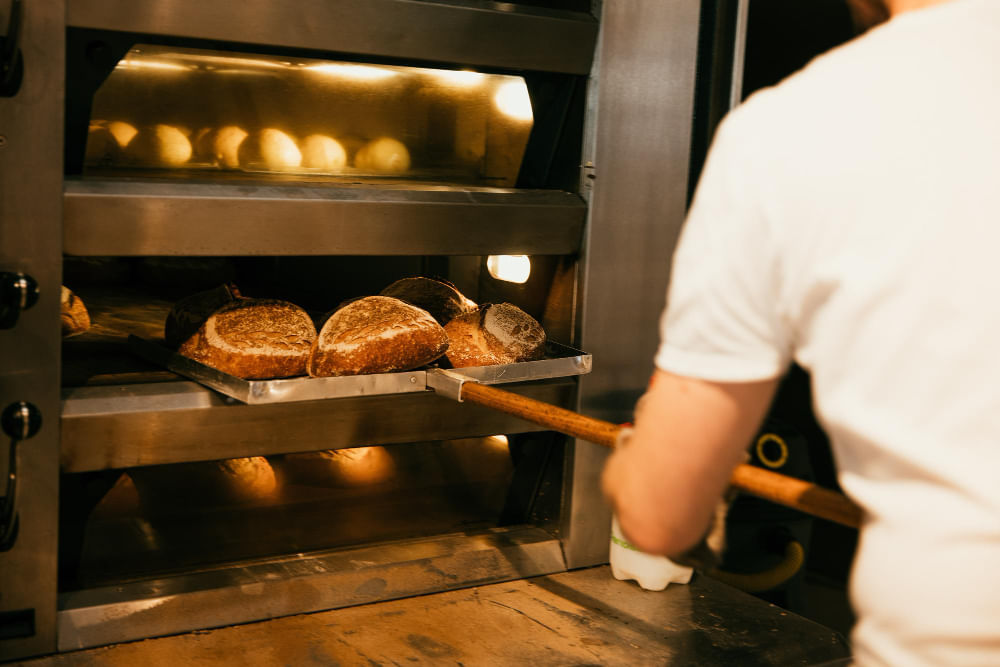 Baker reaching for loaf of bread in the oven in Central Florida