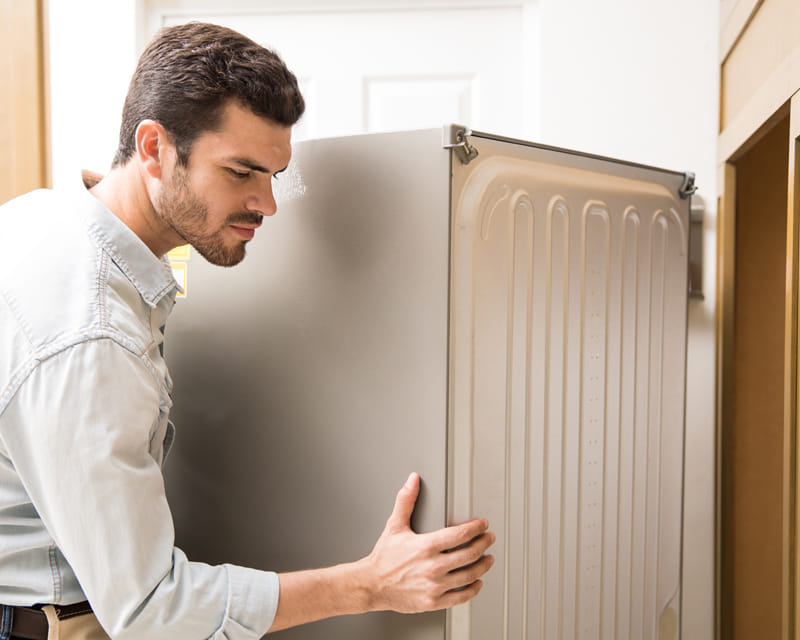 Technician inspecting behind appliances to identify pest entry points in a home. Technician inspecting behind appliances to identify pest entry points in a home.