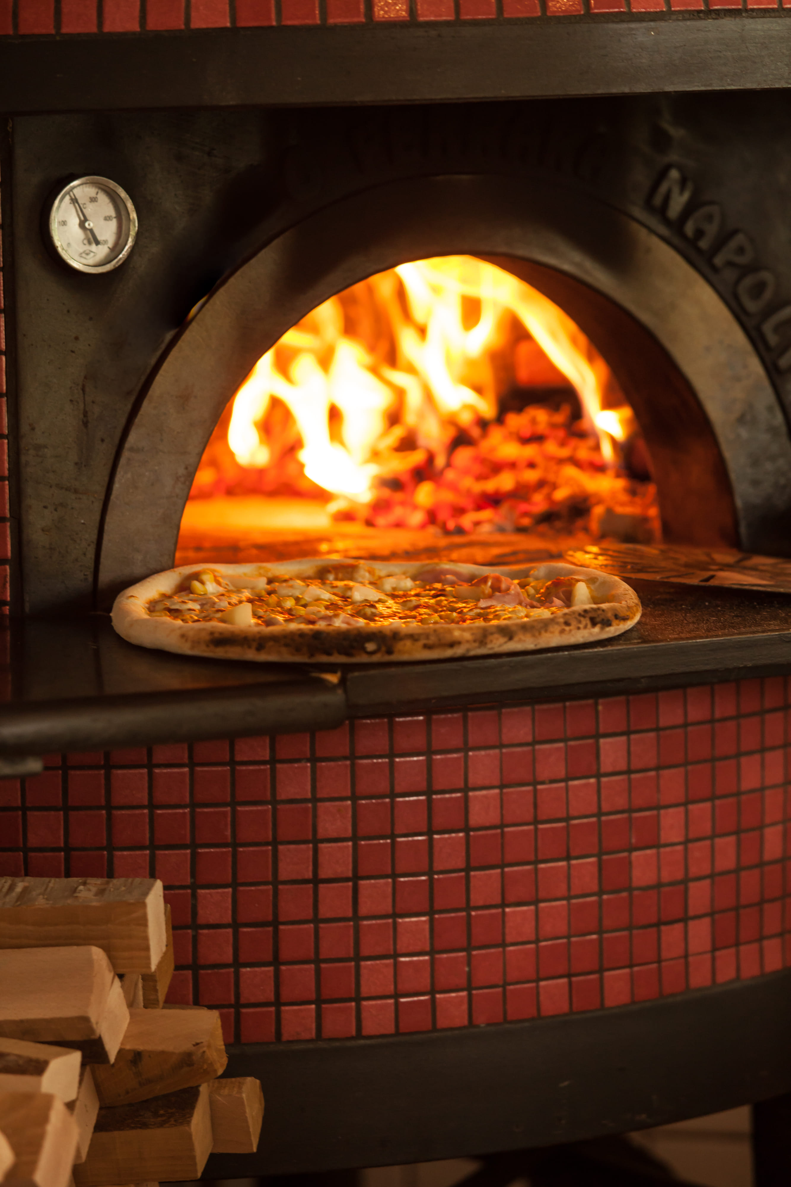 Wood fired pizza oven baking a pizza during commercial kitchen service