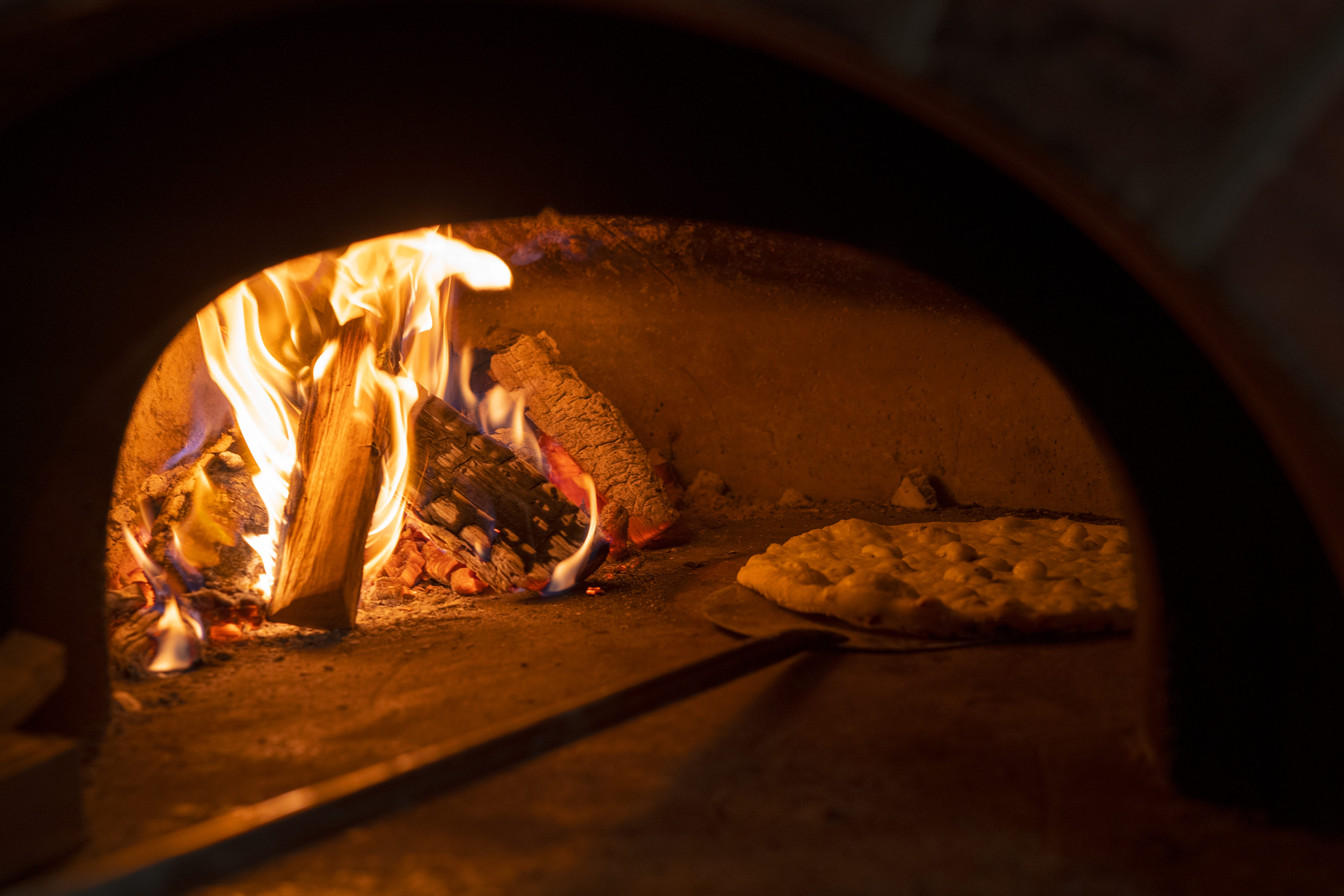 Pizza cooking inside a wood fired commercial oven during restaurant operation
