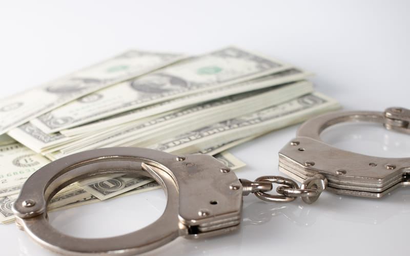 handcuffs laying next to stack of cash