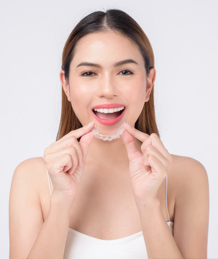 Patient holding a clear orthodontic retainer after treatment Patient holding a clear orthodontic retainer after treatment