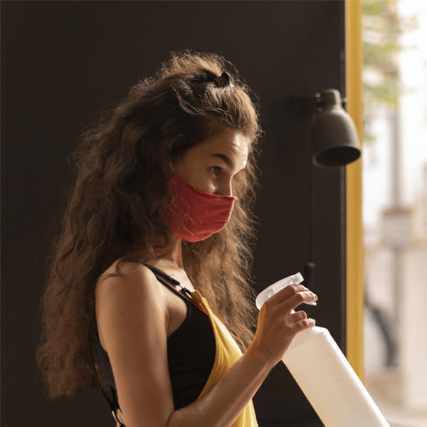 Homeowner using DIY pest control spray indoors with protective mask
