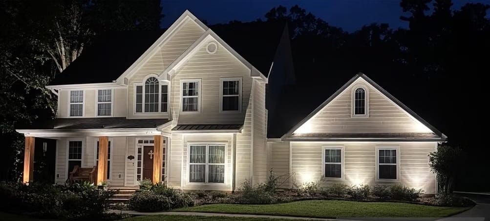 Two-story yellow home in Covington, LA with track lighting underneath each window