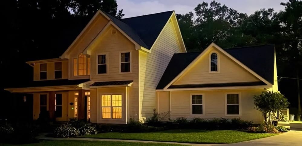 Two-story yellow home with downstairs light on in Covington, LA