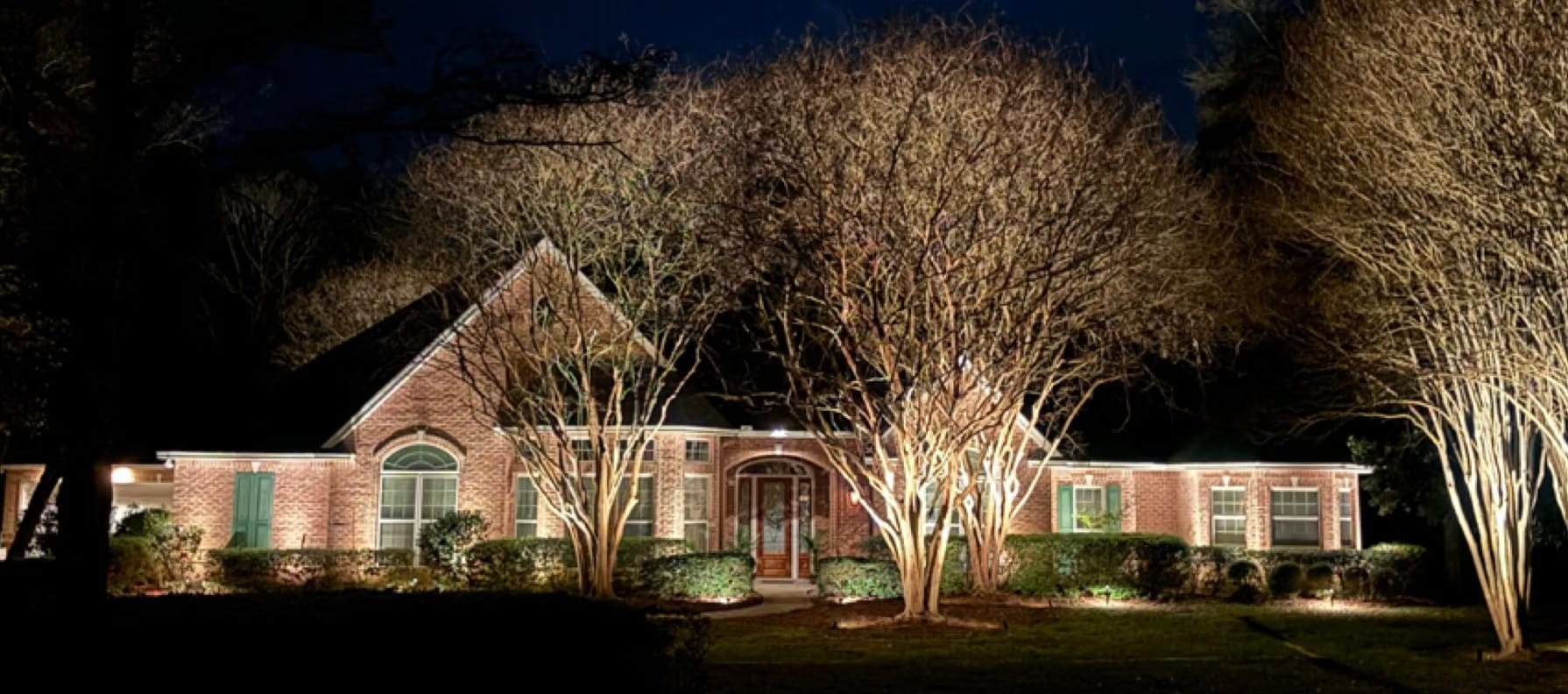 Red brick one-story home in Covington, LA, after the installation of exterior lighting