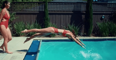woman in red bathing suit diving into pool