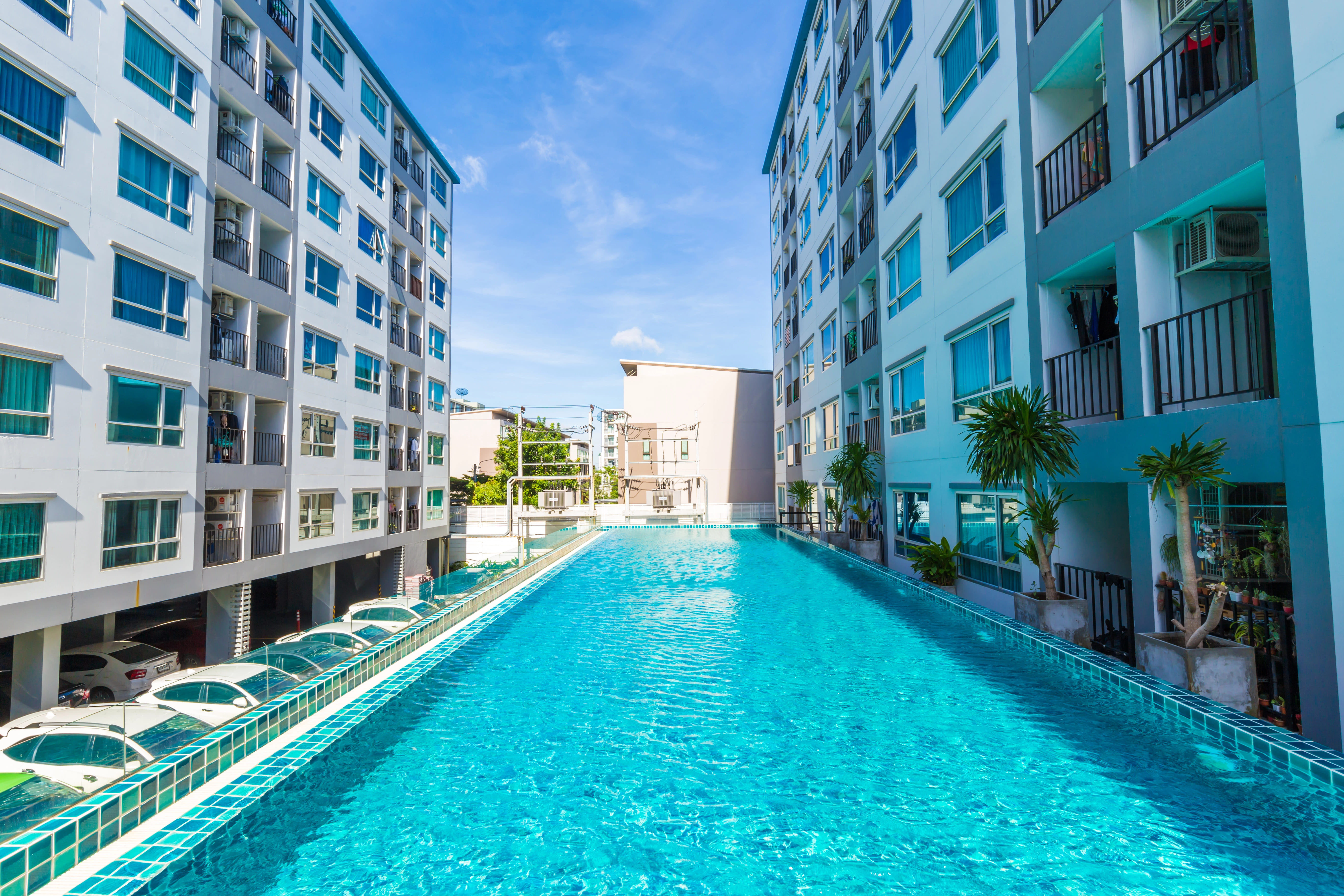 metal ladder placed in blue tile pool between two apartment complex