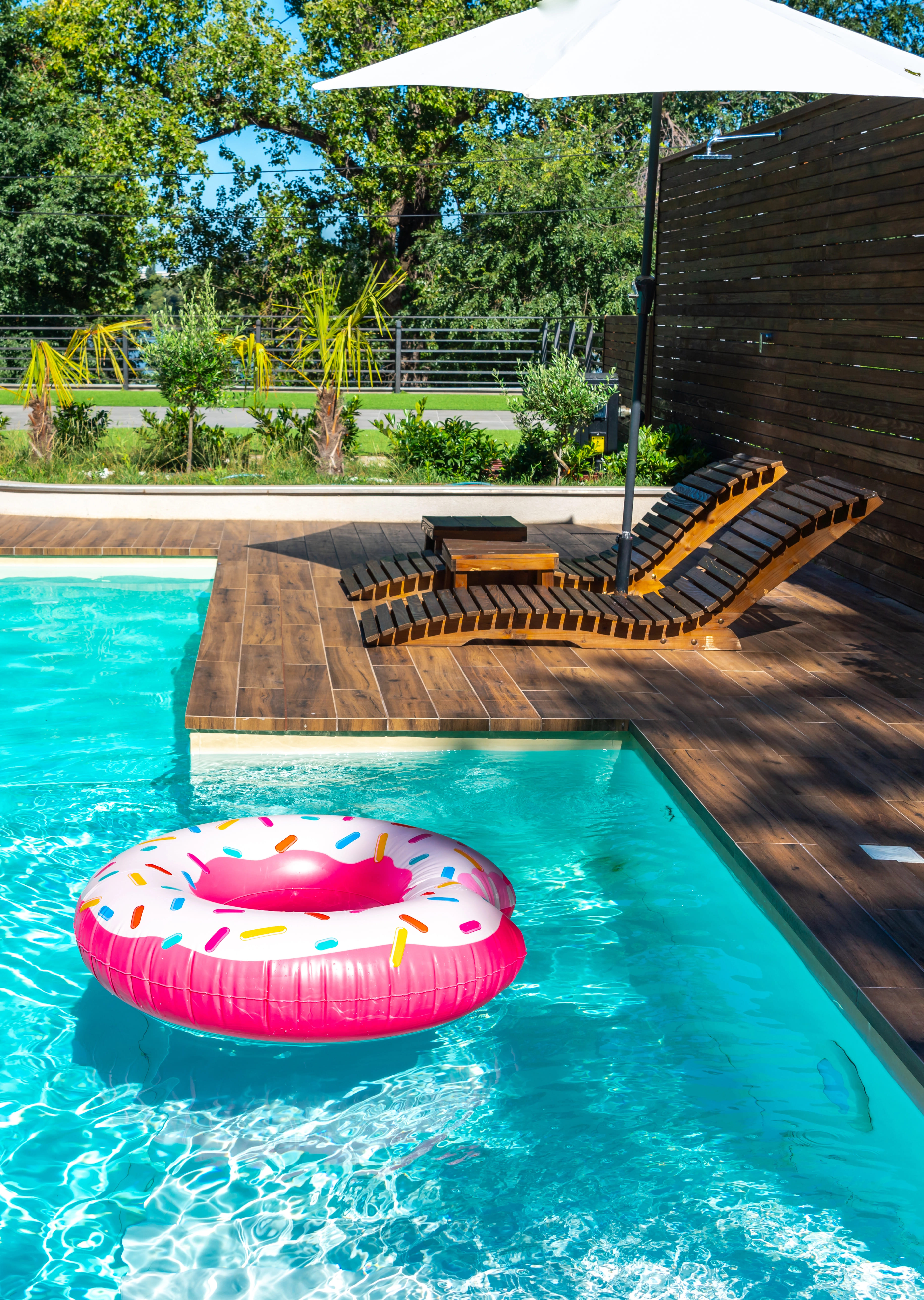 pink donut inflatable table in pool next to deck chairs