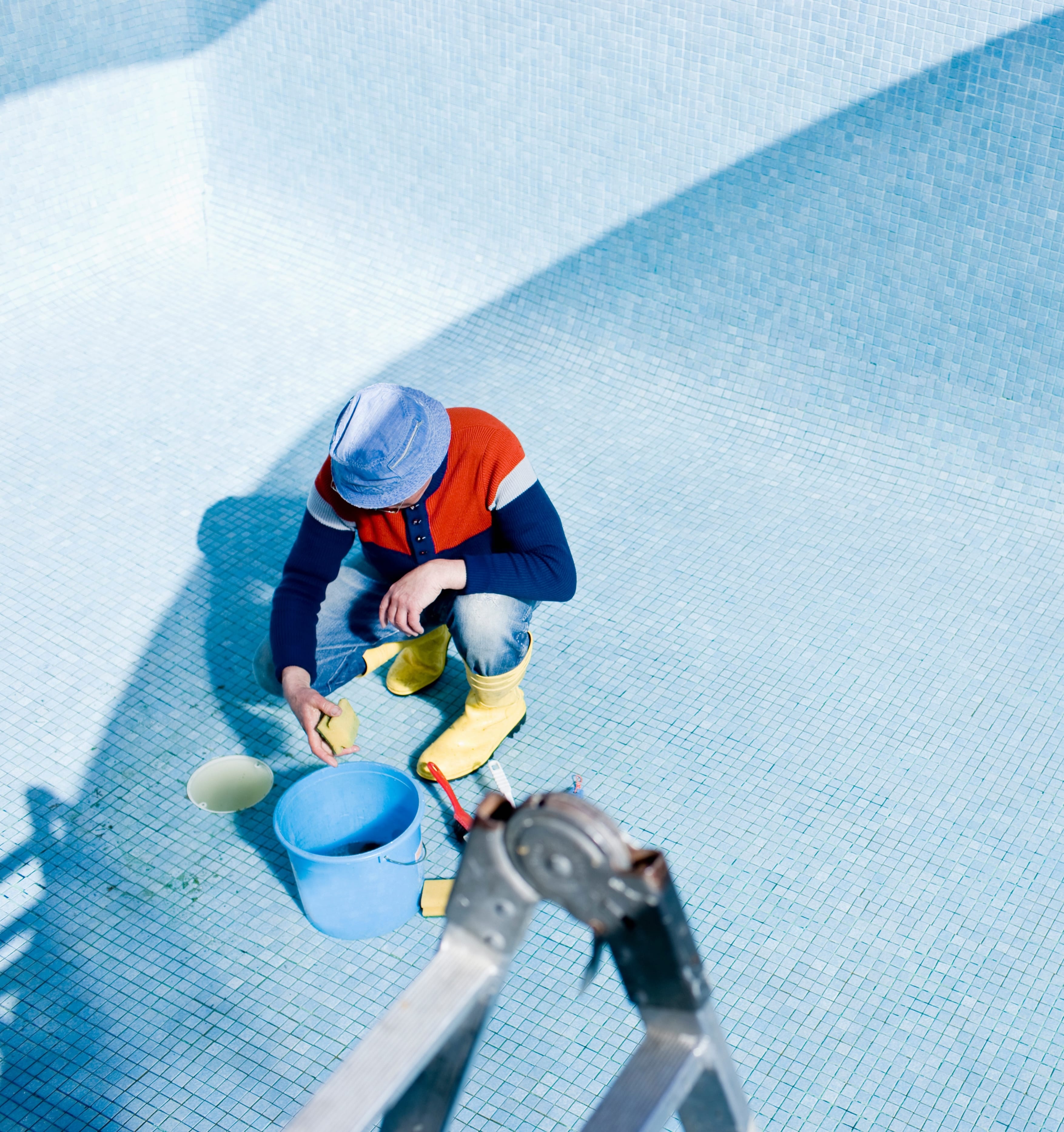 man cleaning and fixing a pool
