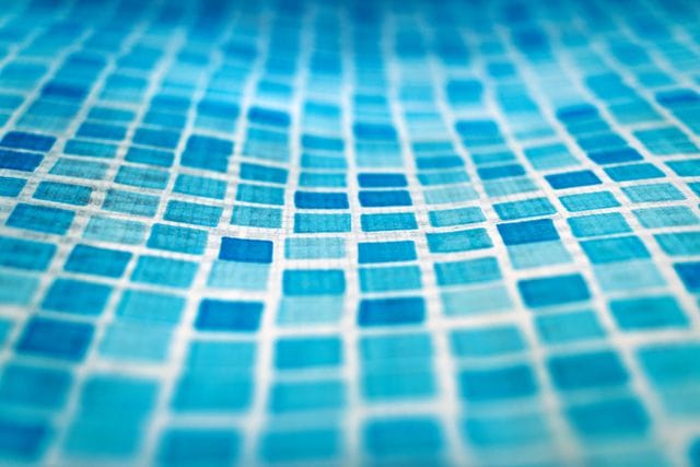 Close-up of blue mosaic pool tiles with white grout