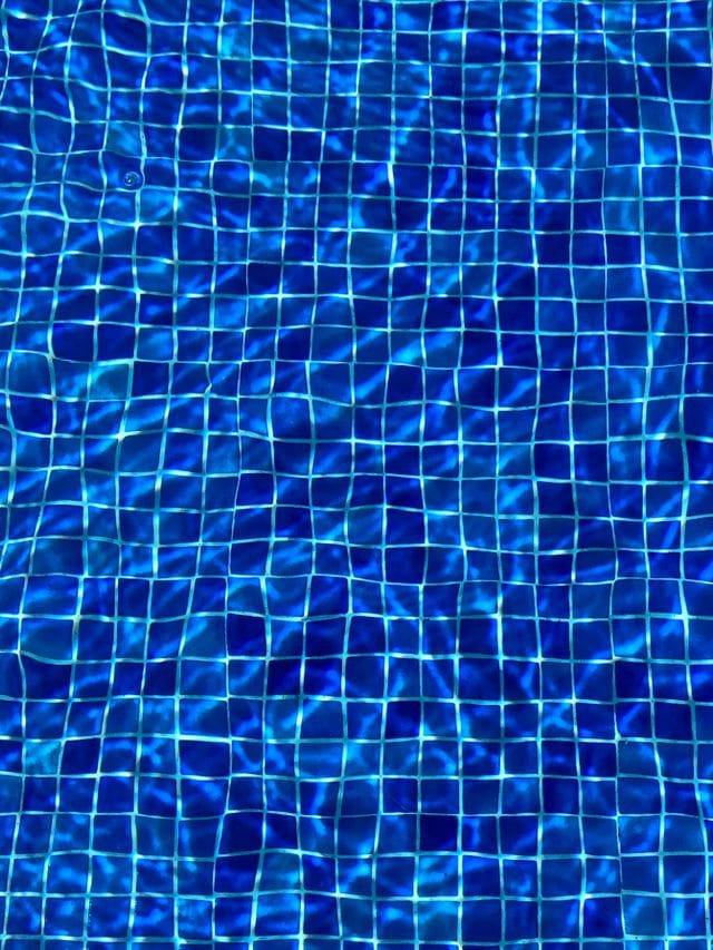Aerial view of blue pool tiles seen through rippling water in St. Louis pool