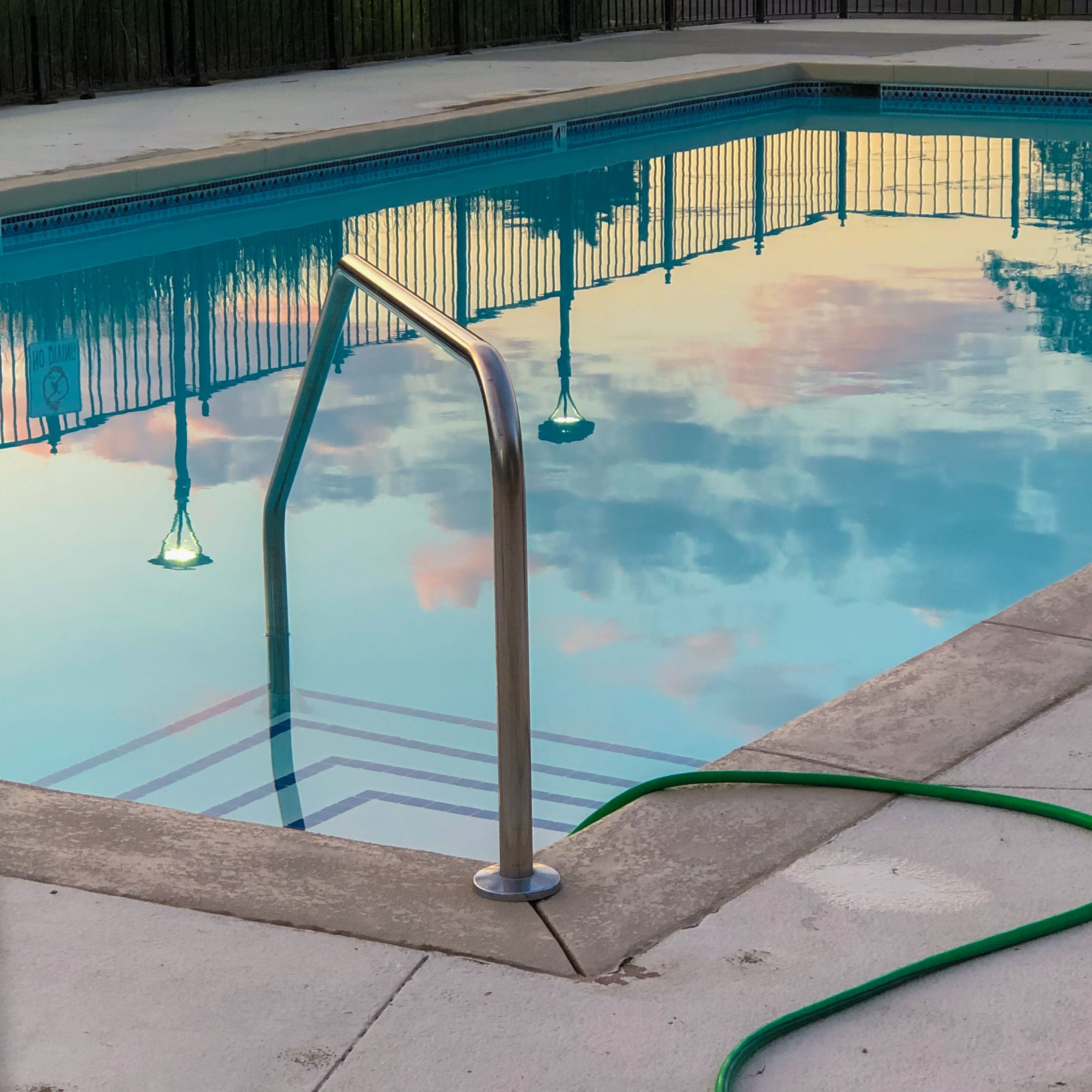 teal tile pool outside an apartment building surrounded by lounge chairs