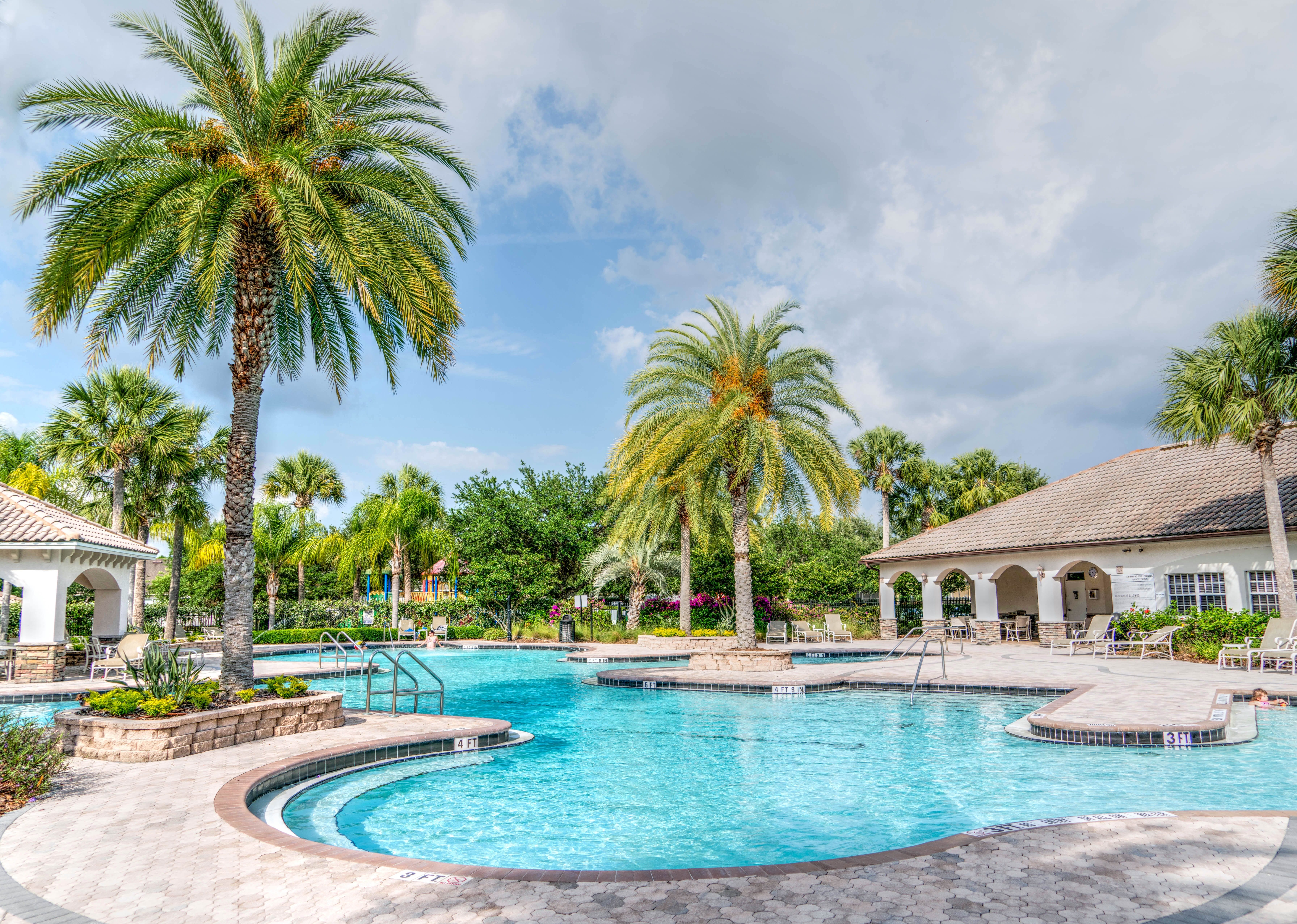 blue water in pool surrounded by tropical trees and a spanish tile gazebo