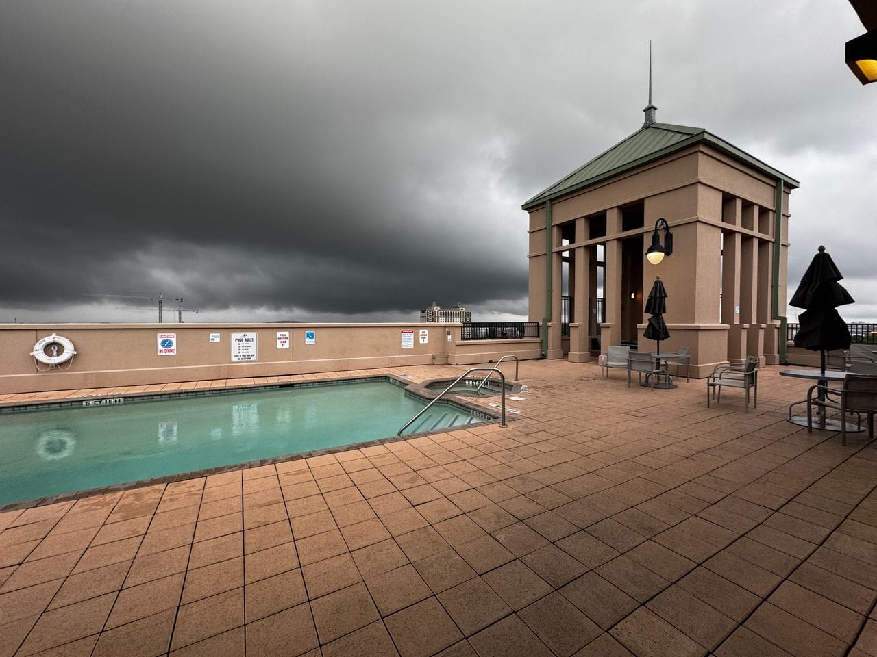 Still water in an inground pool at a hotel as dark storm clouds roll in