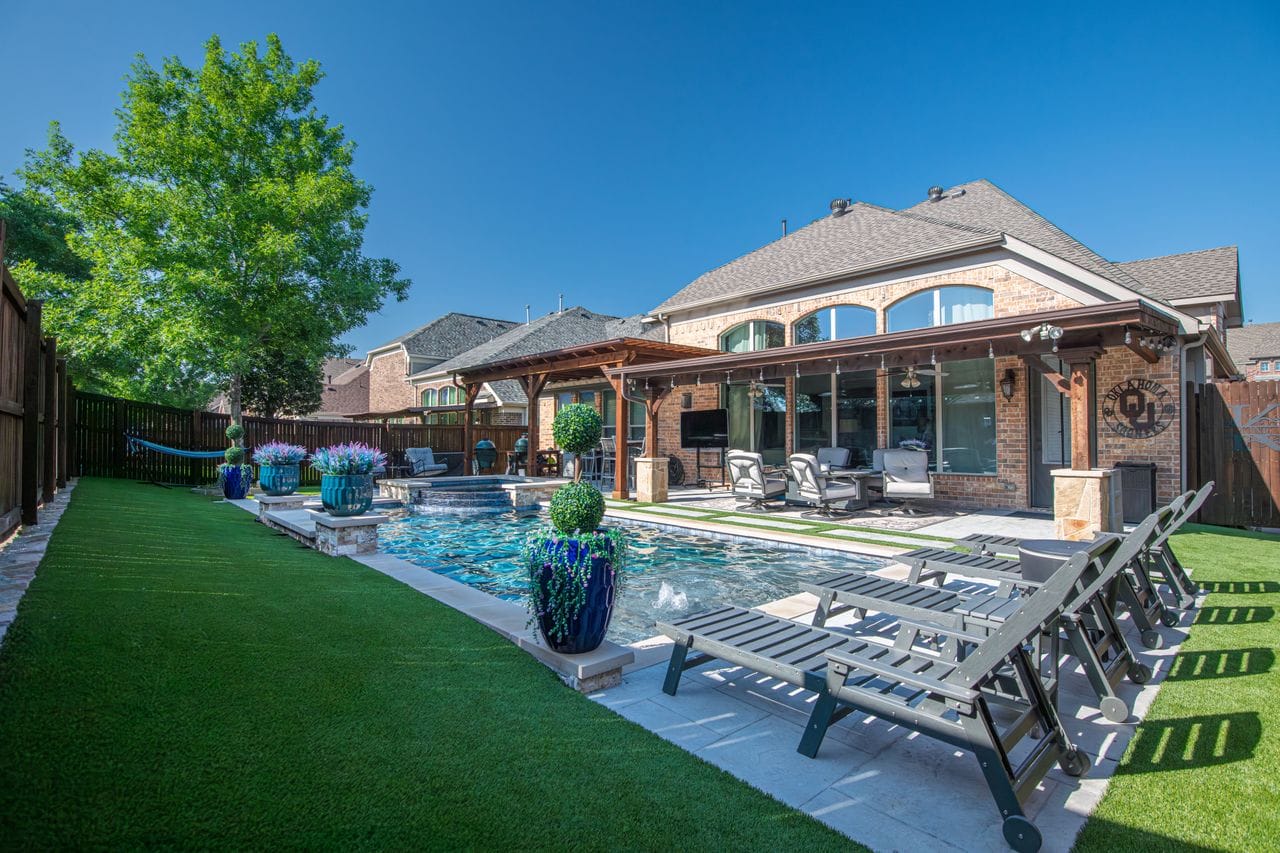 Backyard pool with covered patio, loungers, and outdoor living area